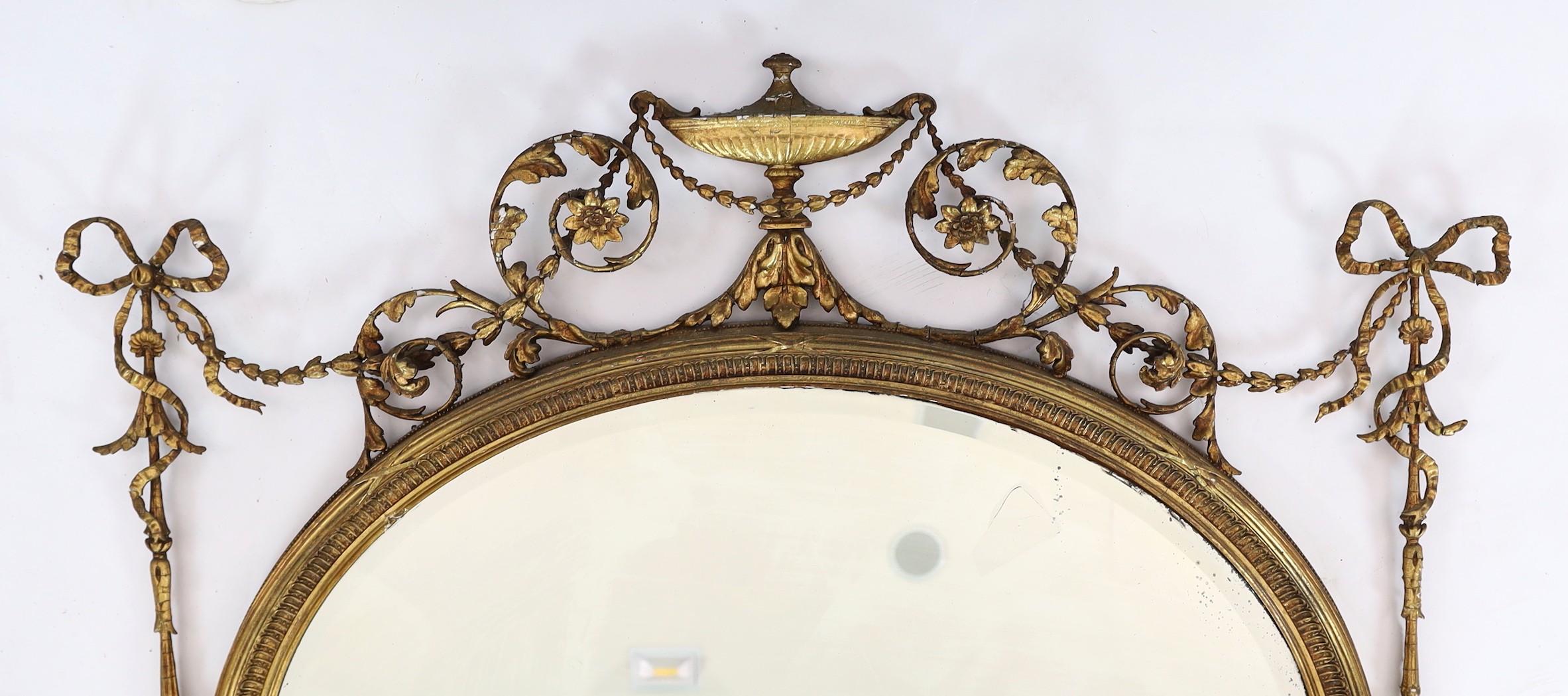 A late Victorian Adam Revival oval wall mirror, width 119cm height 118cm